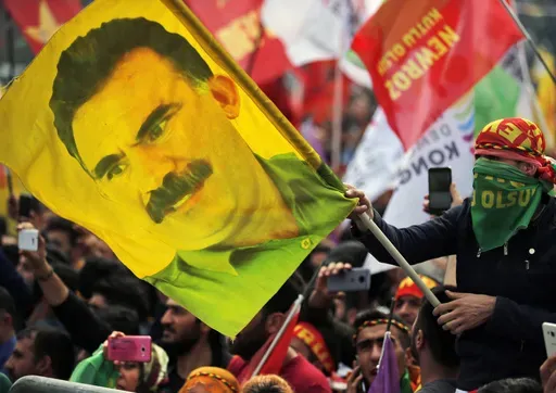In this file photo dated Wednesday, March 21, 2018, a youth holds a flag with the image of Abdullah Ocalan, the jailed leader of the rebel Kurdistan Workers' Party, or PKK, in Istanbul, Turkey. (AP Photo/Lefteris Pitarakis, File)