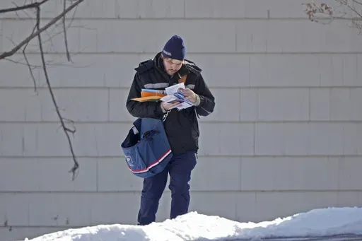 A U.S. Postal Service letter carrier delivers mail, Friday, Feb. 21, 2025, in Overland Park, Kan. (AP Photo/Charlie Riedel, File)