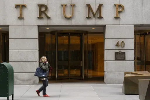 A woman walks past the Trump Building in New York's financial district, Wednesday, Jan. 13, 2021. Mazars USA LLP, the accounting firm that prepared former President Donald Trump’s annual financial statements, says the documents “should no longer be relied upon” after investigators said they found evidence he and his company regularly misstated the value of assets. (AP Photo/Mark Lennihan, File)