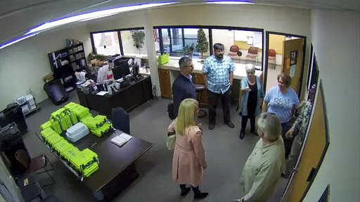 This Jan. 7, 2021, image taken from Coffee County, Ga., security video, appears to show Cathy Latham (center, long turquoise top), introducing members of a computer forensic team to local election officials. Latham was the county Republican Party chair at the time. The computer forensics team was at the county elections office in Douglas, Ga., to make copies of voting equipment in an effort that documents show was arranged by attorney Sidney Powell and others allied with then-President Donald Tr