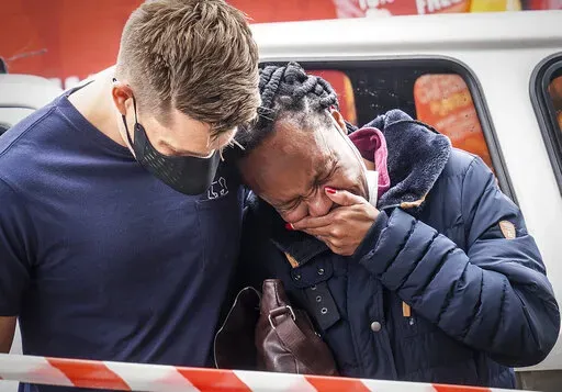 A woman is comforted outside the historical home of Anglican Archbishop Desmond Tutu, in Soweto, Johannesburg, South Africa, Monday, Dec. 27, 2021. South Africa's president says Tutu, South Africa's Nobel Peace Prize-winning activist for racial justice and LGBT rights and the retired Anglican Archbishop of Cape Town, died Sunday at the age of 90. (AP Photo/Shiraaz Mohamed)