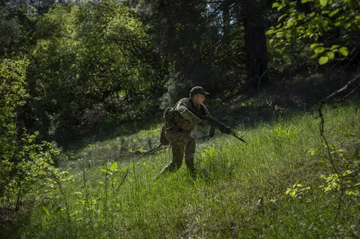 A Ukrainian Border Guard soldier participates in a military exercise in central Ukraine, Monday, May 1, 2023. Ahead of the much-anticipated Ukrainian counter-offensive, newly formed military assault units train in the country's dense forests. (AP Photo/Bernat Armangue)