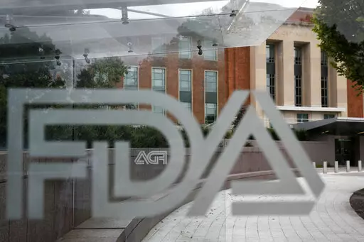 This Aug. 2, 2018 file photo shows the U.S. Food and Drug Administration building behind FDA logos at a bus stop on the agency's campus in Silver Spring, Md. The Food and Drug Administration has issued a negative review of a closely watched experimental drug for the debilitating illness known as Lou Gehrig’s disease. The review comes ahead of a meeting this week for outside experts to vote on the drug for ALS. The drug has been the focal point of a lobbying campaign by patients, their families