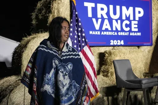 A Native American woman walks by the stage during a campaign event in support of Republican presidential nominee former President Donald Trump, Friday, Oct. 18, 2024, in Red Springs, N.C. (AP Photo/David Yeazell)