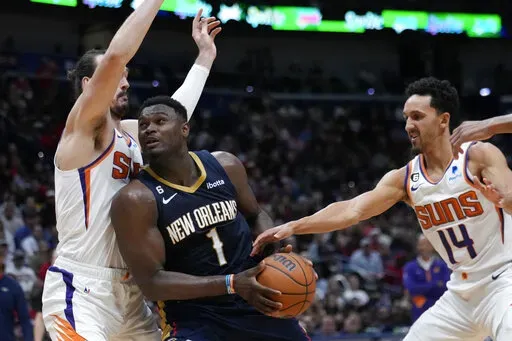 New Orleans Pelicans forward Zion Williamson (1) drives to the basket between Phoenix Suns forward Dario Saric and guard Damion Lee (10) in the second half of an NBA basketball game in New Orleans, Sunday, Dec. 11, 2022. The Pelicans won 129-124. (AP Photo/Gerald Herbert)