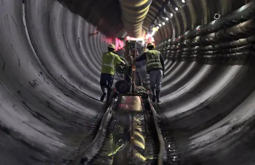 Tunnel workers push equipment up a rail track to a machine boring a 2.5-mile bypass tunnel for the Delaware Aqueduct in Marlboro, N.Y., May 16, 2018. (AP Photo/Julie Jacobson, File)