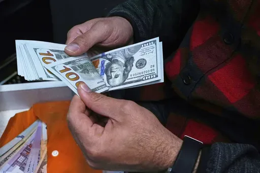 A currency exchange bureau worker counts U.S. dollars at Ferdowsi square, Tehran's go-to venue for foreign currency exchange, in downtown Tehran, Iran, Saturday, April 5, 2025. (AP Photo/Vahid Salemi)