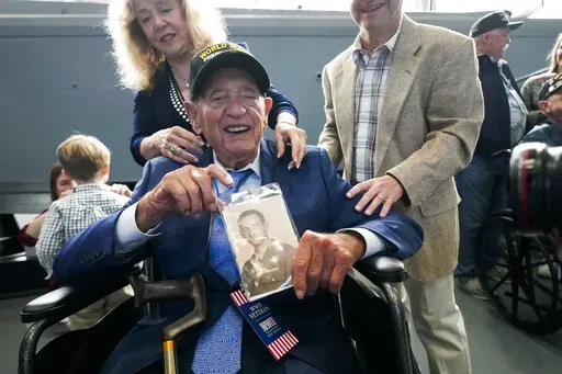 World War II veteran Joseph Eskenazi, who at 104 years and 11 months old is the oldest living veteran to survive the attack on Pearl Harbor, holds a photo of his younger self, at an event celebrating his upcoming 105th birthday at the National World War II Museum in New Orleans, Wednesday, Jan. 11, 2023. (AP Photo/Gerald Herbert)