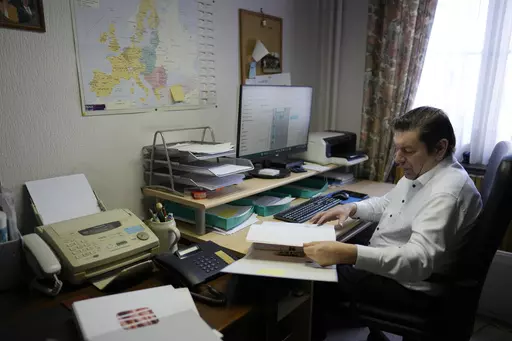 Bart Dochy looks through accounting books and logs entries on his computer at his family farm in Ledegem, Belgium, Tuesday, Feb. 13, 2024. Fickle regulations are a key complaint heard from European farmers protesting over the past weeks, setting up a key theme for the upcoming June 6-9 parliamentary elections in the 27-nation European Union. (AP Photo/Virginia Mayo)