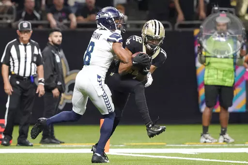New Orleans Saints wide receiver Chris Olave catches a touchdown pass from quarterback Andy Dalton as Seattle Seahawks cornerback Coby Bryant defends during an NFL football game in New Orleans, Sunday, Oct. 9, 2022. (AP Photo/Gerald Herbert)