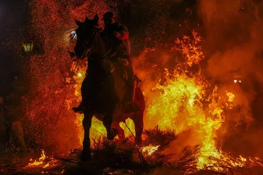 A man rides a horse through a bonfire as part of a ritual in honor of Saint Anthony the Abbot, the patron saint of domestic animals, in San Bartolome de Pinares, Spain, Thursday, Jan. 16, 2025. (AP Photo/Manu Fernandez)