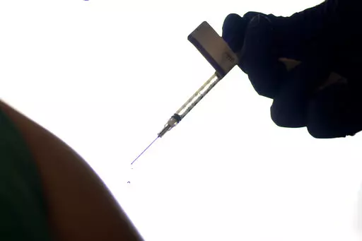 A droplet falls from a syringe after a health care worker was injected with the Pfizer-BioNTech COVID-19 vaccine at Women & Infants Hospital in Providence, R.I., on Dec. 15, 2020. On Friday, June 10, 2022, The Associated Press reported on stories circulating online incorrectly claiming that 20,000 people have died from COVID-19 vaccines. The figure misrepresents data maintained by the Centers for Disease Control and Prevention and the Food and Drug Administration. To date, a total of nine deaths