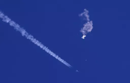 A fighter jet flies past the remnants of a large balloon after it was shot down above the Atlantic Ocean, just off the coast of South Carolina near Myrtle Beach, Feb. 4, 2023. The Defense Department and the Federal Aviation Administration have been tracking a balloon that was flying off the coast of Hawaii last week. A defense official says there’s no indication it is connected to China or any other adversary, and it presents no threats to aviation or national security. (Chad Fish via AP, File