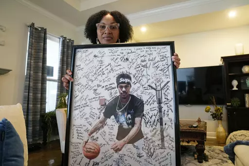 Pamela White poses in her home in Ponchatoula, La., with a photo of her son Dararius Evans, who was killed in January of 2020, Thursday, May 4, 2023. White and her family turned to Louisiana’s victim compensation board for help paying for the unexpected funeral. She was met with administrative hurdles, a denial that blamed her son for his own death, a lengthy appeal — all while paying up front through a personal loan that gathered interest as she waited. (AP Photo/Gerald Herbert)
