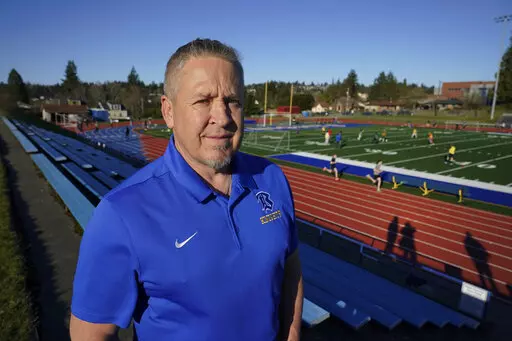 Joe Kennedy, a former assistant football coach at Bremerton High School in Bremerton, Wash., poses for a photo March 9, 2022, at the school's football field. After losing his coaching job for refusing to stop kneeling in prayer with players and spectators on the field immediately after football games, Kennedy will take his arguments before the U.S. Supreme Court on Monday, April 25, 2022, saying the Bremerton School District violated his First Amendment rights by refusing to let him continue pra