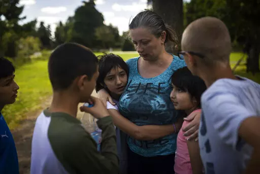 Olga Lopatkina embraces her adopted children in a park in Loue, western France, Saturday, July 2, 2022. After two months of negotiation and an initial objection from a senior Russian official, DPR authorities finally agreed to allow a volunteer with power of attorney from Lopatkina to collect her children who were evacuated from Mariupol. An Associated Press investigation has found that Russia’s strategy to take Ukrainian orphans and bring them up as Russian is well underway. (AP Photo/Jeremia
