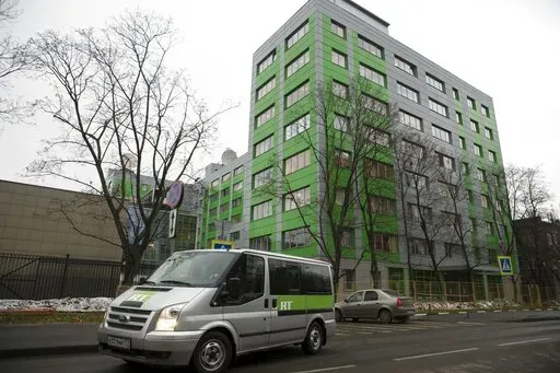 In this file photo taken on Friday, Oct. 27, 2017, a car of Russian state-owned television station RT passes by the company's office in Moscow, Russia. Britain’s communications regulator has revoked the license of Russian-backed broadcaster RT amid investigations of its coverage of the Ukraine war. The regulator, Ofcom, said it a statement that it did not consider RT’s licensee, ANO TV Novosti, to be “fit and proper to hold a U.K. broadcast license.” (AP Photo/Pavel Golovkin, FILE)