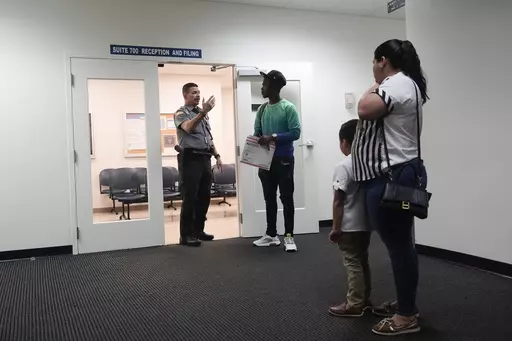 An officer directs people to a courtroom, Jan. 10, 2024, in an immigration court in Miami. A 53-year-old union of immigration judges has been ordered to get supervisor approval to speak publicly to anyone outside the Justice Department, potentially quieting a frequent critic of heavily backlogged immigration courts in an election year. (AP Photo/Wilfredo Lee, File)