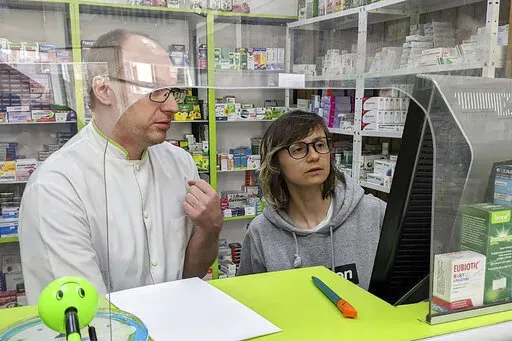 Sasha Kaverina, right, buys medicine in Romania for displaced Ukrainians on March 26, 2022. As millions of Ukrainians fled their country, a longtime Tokyo resident did the opposite. Kaverina left her life in Japan and rushed to Ukraine to rescue her parents after a Russian missile hit their apartment building. (Courtesy of Alina Anokhina via AP)