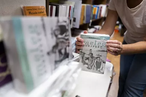 An employee of a bookstore wraps a book featuring LGBTQ+ content in closed packaging to comply with a contentious law on homosexuality in media, on Wednesday, July 26, 2023 in Budapest, Hungary. Booksellers in Hungary must decide whether to comply with a law requiring books that depict homosexuality to be placed in closed packaging on their shelves. Some bookstores have already received hefty fines from the right-wing government for failing to do so, while others have opted to abide by the legis