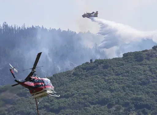 A CL 415 scooper, top, drops water on the Quarry Fire as a Firehawk helicopter maneuvers for a water drop Thursday, Aug. 1, 2024, southwest of Littleton, Colo. (Andy Cross/The Denver Post via AP)