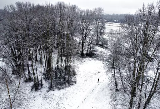 A trail of footprints lead from the parking lot to the water as freshly-fallen snow blankets Frenchman's Bar Regional Park in Vancouver, Wash., on Tuesday, Dec. 28, 2021. The winter storm dropped between 1 and 2 inches of snow on the city. (Amanda Cowan/The Columbian via AP)