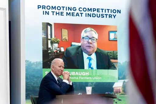 President Joe Biden attends a virtual meeting with family and independent farmers and ranchers including Scott Blubaugh, President, Oklahoma Farmers Union, visible on the monitor, at the South Court Auditorium in the Eisenhower Executive Office Building on the White House Campus in Washington, Monday, Jan. 3, 2022, to discuss work to boost competition and reduce prices in the meat-processing industry. (AP Photo/Andrew Harnik)