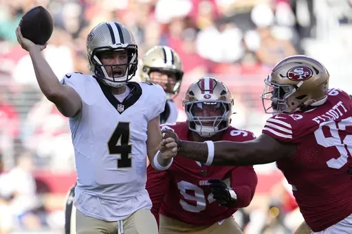 New Orleans Saints quarterback Derek Carr (4) passes as San Francisco 49ers defensive end Yetur Gross-Matos, middle, and defensive tackle Jordan Elliott apply pressure during the first half of a preseason NFL football game in Santa Clara, Calif., Sunday, Aug. 18, 2024. (AP Photo/Godofredo A. Vásquez)
