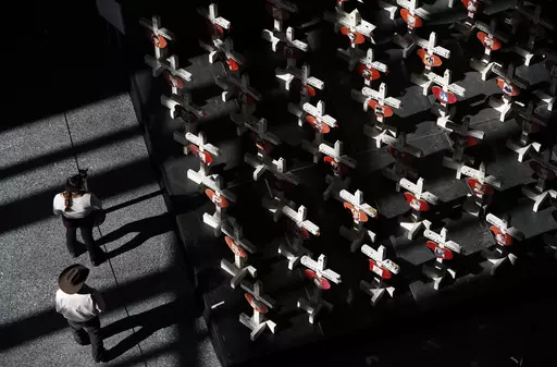 In this Sept. 25, 2018, photo, people look at a display of wooden crosses and a Star of David on display at the Clark County Government Center in Las Vegas. It was the deadliest mass shooting in modern U.S. history on the Las Vegas Strip in 2017. More than 100 people have been killed in mass shootings thus far in 2023, an average of one mass killing a week. (AP Photo/John Locher, File)