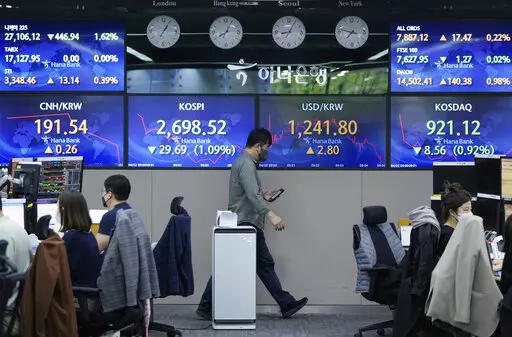 A currency trader passes by screens showing the Korea Composite Stock Price Index (KOSPI), center left, and the foreign exchange rate between U.S. dollar and South Korean won, at the foreign exchange dealing room of the KEB Hana Bank headquarters in Seoul, South Korea, Friday, April 22, 2022. Asian shares fell Friday, tracking losses on Wall Street after Federal Reserve Chair Jerome Powell indicated increases in interest rates must be faster to fight inflation. (AP Photo/Ahn Young-joon)
