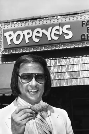 Popeyes founder Al Copeland holds a piece of his fried chicken outside one of his 34 fast food outlets in New Orleans on June 20, 1979. A new book, “Secrets of a Tastemaker: Al Copeland, The Cookbook," released last month, helped mark the 50th anniversary of Popeyes Famous Fried Chicken. (AP Photo, File)