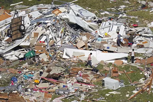 In this aerial photo, people walk amidst destruction from a tornado that struck on Tuesday night in Arabi, La., Wednesday, March 23, 2022. Residents of severely damaged or destroyed homes in Arabi swept up broken glass and tried to salvage their belongings. (AP Photo/Gerald Herbert)