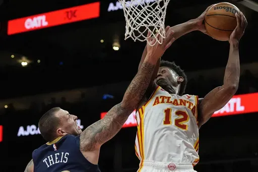 Atlanta Hawks forward De'Andre Hunter (12) grabs a rebound from New Orleans Pelicans center Daniel Theis (10) during the first half of an NBA basketball game, Monday, Dec. 2, 2024, in Atlanta. (AP Photo/Mike Stewart)
