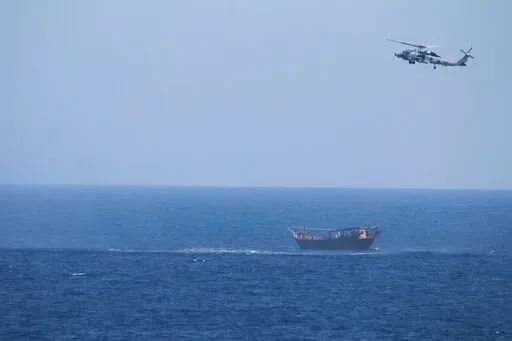 A U.S. Navy Seahawk helicopter flies over a stateless dhow later found to be carrying a hidden arms shipment in the Arabian Sea, May 6, 2021. The U.S. Navy's Mideast-based 5th Fleet will begin Tuesday, July 5, 2022, to offer rewards for information that could help sailors intercept weapons, drugs and other illicit shipments across the region. The program launches against the backdrop of tensions over Iran’s nuclear program and Tehran’s arming of Yemen’s Houthi rebels. (U.S. Navy via AP, Fi