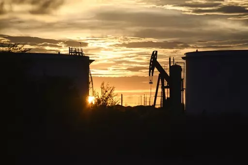 The sun begins to set behind crude oil tanks and a pumpjack, July 5, 2022, in Midland, Texas. The IEA’s annual world energy outlook, which analyzes the global picture of energy supply and demand, was released Tuesday, Oct. 24, 2023. (Eli Hartman/Odessa American via AP, File)