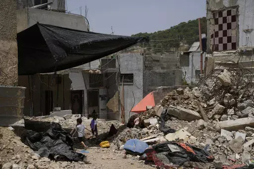 Palestinian children play by the rubble of buildings that were destroyed during Israeli army operations in the Nur Shams refugee camp in the West Bank on May 20, 2024. (AP Photo/Nasser Nasser)