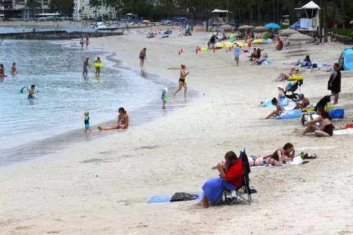 People sit on Waikiki Beach in Honolulu, Aug. 24, 2021. Honolulu police recently got some attention on social media for recommending that beachgoers not leave their valuables unattended and instead put them in a waterproof bag and take them into the ocean. (AP Photo/Caleb Jones, File)