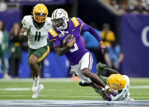 LSU wide receiver Chris Hilton Jr., center, gets past a tackle by Baylor cornerback LeVar Thornton Jr., bottom right, for a gain during the first half of the Texas Bowl NCAA college football game Tuesday, Dec. 31, 2024, in Houston. (Brett Coomer/Houston Chronicle via AP)