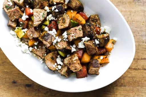 This image released by Milk Street shows a recipe for Chili-rubbed Pork with Cucumber-Melon Salad. (Milk Street via AP)