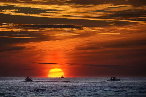 The sun rises over fishing boats in the Atlantic Ocean, Sept. 8, 2022, off of Kennebunkport, Maine. The United Nations body that regulates the world’s ocean floor is preparing to resume negotiations in July 2023, that could open the international seabed for mining, including for materials vital for the green energy transition. (AP Photo/Robert F. Bukaty, File)