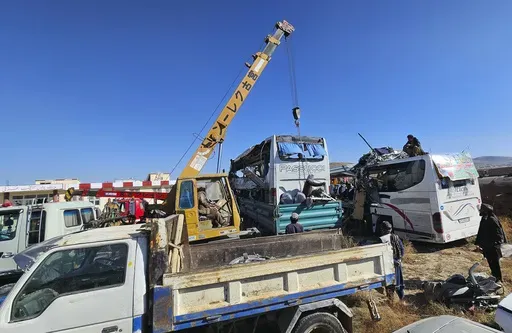 People remove damaged buses after an accident in Ghazni province, southeastern Afghanistan, Thursday, Dec. 19, 2024. (AP Photo/Gulabuddin Amiri)