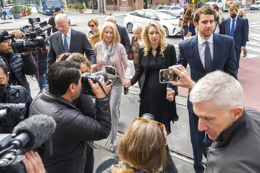 Theranos founder and CEO Elizabeth Holmes, center, walks into federal court with her partner Billy Evans, right, and her parents in San Jose, Calif., Friday, Nov. 18, 2022.  A federal judge will decide whether Holmes should serve a lengthy prison sentence for duping investors and endangering patients while peddling a bogus blood-testing technology. 
 (AP Photo/Nic Coury)