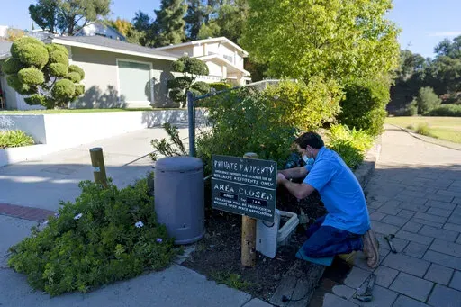 CORRECTS SPELLING TO AGOURA HILLS NOT AGORA HILLS Cason Gilmer, a senior field customer service representative from the Las Virgenes Municipal Water District, installs an advanced water metering system in Agoura Hills , Calif., Wednesday, Jan. 5, 2022. The wealthy enclave along the Santa Monica Mountains that is haven for celebrities has taken aggressive steps to try to limit water use during California's drought, including lowering the thresholds for fines for those who go over their "water bud