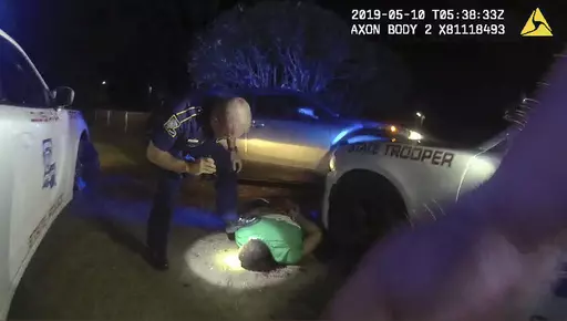 In this image from video from Louisiana state police state trooper Dakota DeMoss' body-worn camera, trooper Kory York bends over with his foot on Ronald Greene's shoulder after he was taken into custody on May 10, 2019, outside of Monroe, La. On Monday, Oct. 9, 2023, a judge delivered a victory to the state prosecution of white Louisiana lawmen in the deadly 2019 arrest of Ronald Greene, allowing the most serious charge of negligent homicide to go forward against York, captured on video dragging