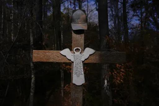 Willie Crayton's hat hangs on a cross bearing the Lord's Prayer and marking the location along Elder Road, Thursday, Dec. 5, 2024, in Dadeville, Ala, where the Alexander City Community Work Center transport van he was riding in crashed in April 2024, killing Crayton and Bruce Clements. (AP Photo/Carolyn Kaster)