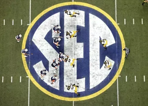 Auburn quarterback Nick Marshall (14), left, takes the snap from Auburn center Reese Dismukes (50) as the Auburn offense operates against Missouri on the SEC logo during the first half of Auburn's 59-42 win over Missouri in the SEC Championship at the Georgia Dome, Saturday, Dec. 7, 2013, in Atlanta, Ga. Southeastern Conference and Pac-12 officials are expected to provide the final approval of a $2.8 billion plan that will settle antitrust claims and set the stage for college athletes to start s