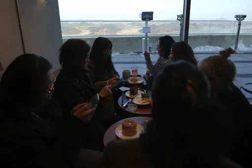 Visitors sit at a newly opened Starbucks store as North Korea's Kaephung county is seen in the background at the observatory of the Aegibong Peace Ecopark in Gimpo, South Korea, Friday, Nov. 29, 2024. (AP Photo/Lee Jin-man)