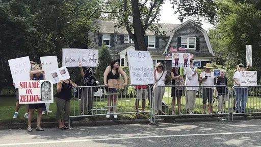 Protesters stand along a street on Long Island in Southampton, N.Y. on Friday, Aug. 17, 2018, near the location of a campaign fundraiser attended by President Donald Trump. (AP Photo/Sara Gillesby, File)