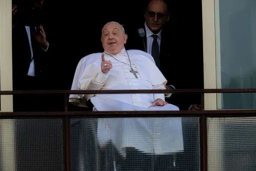 Pope Francis gestures as he appears at a window of the Agostino Gemelli Polyclinic in Rome, Sunday, March 23, 2025, where he has been treated for bronchitis and bilateral pneumonia since Feb. 14. (AP Photo/Domenico Stinellis)