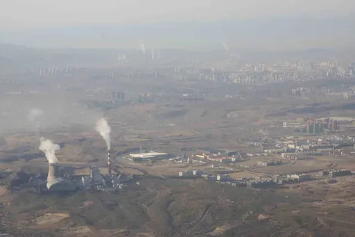 Smoke and steam rise from towers at the coal-fired Urumqi Thermal Power Plant as seen from a plane in Urumqi in western China's Xinjiang Uyghur Autonomous Region on April 21, 2021. China is promoting coal-fired power as the ruling Communist Party tries to revive a sluggish economy, prompting warnings that Beijing is setting back efforts to cut climate-changing carbon emissions from the biggest global source. (AP Photo/Mark Schiefelbein, File)